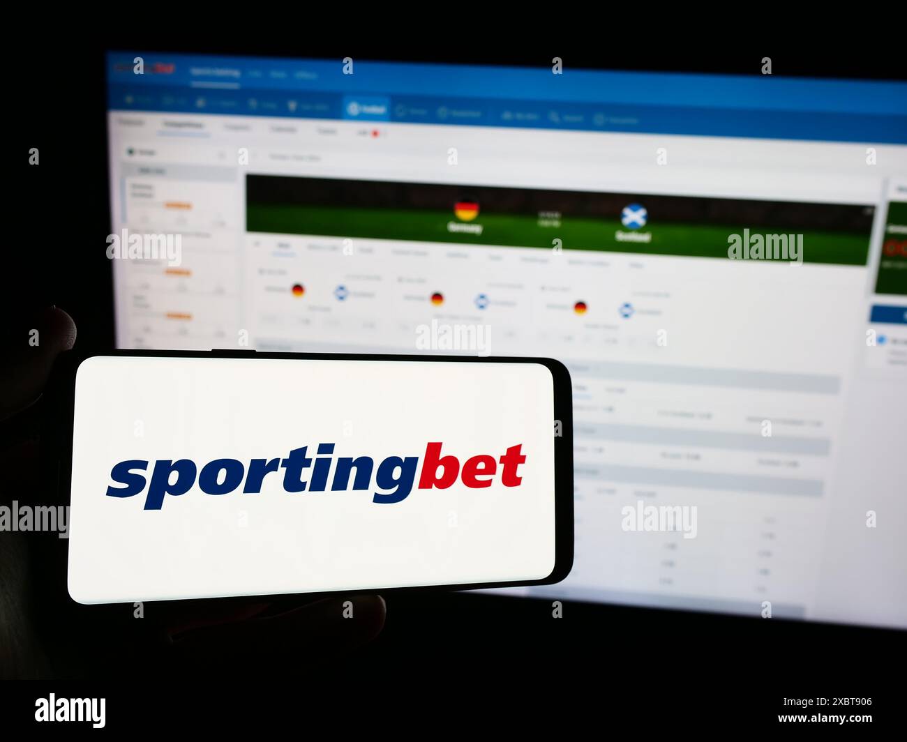 Person mit Smartphone und Logo des britischen Sportwettenunternehmens Sportingbet plc vor der Website. Schwerpunkt auf dem Display des Telefons. Stockfoto