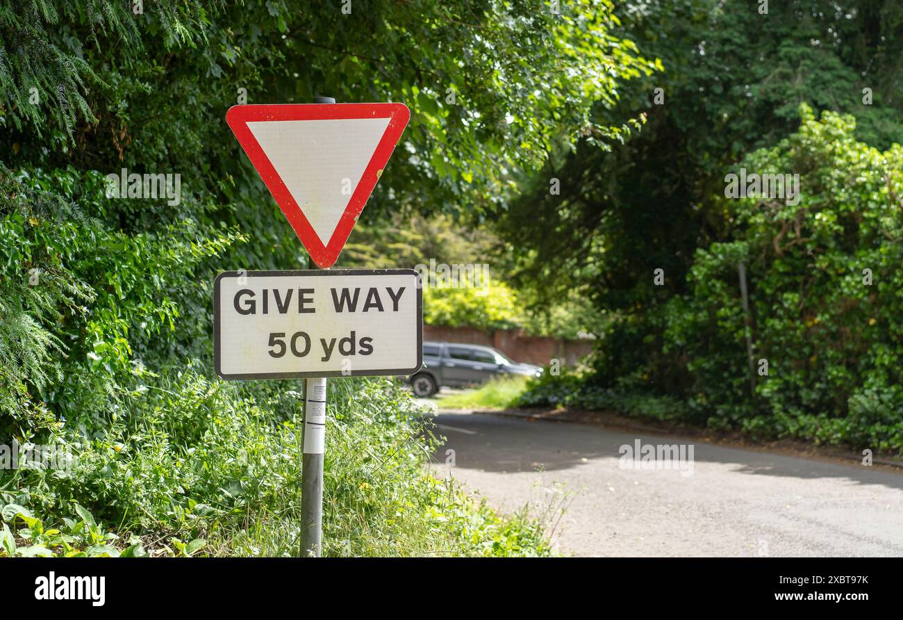 Britisches dreieckiges WEGSCHILD an einer Landkreuzung mit einem Auto im Hintergrund. Stockfoto