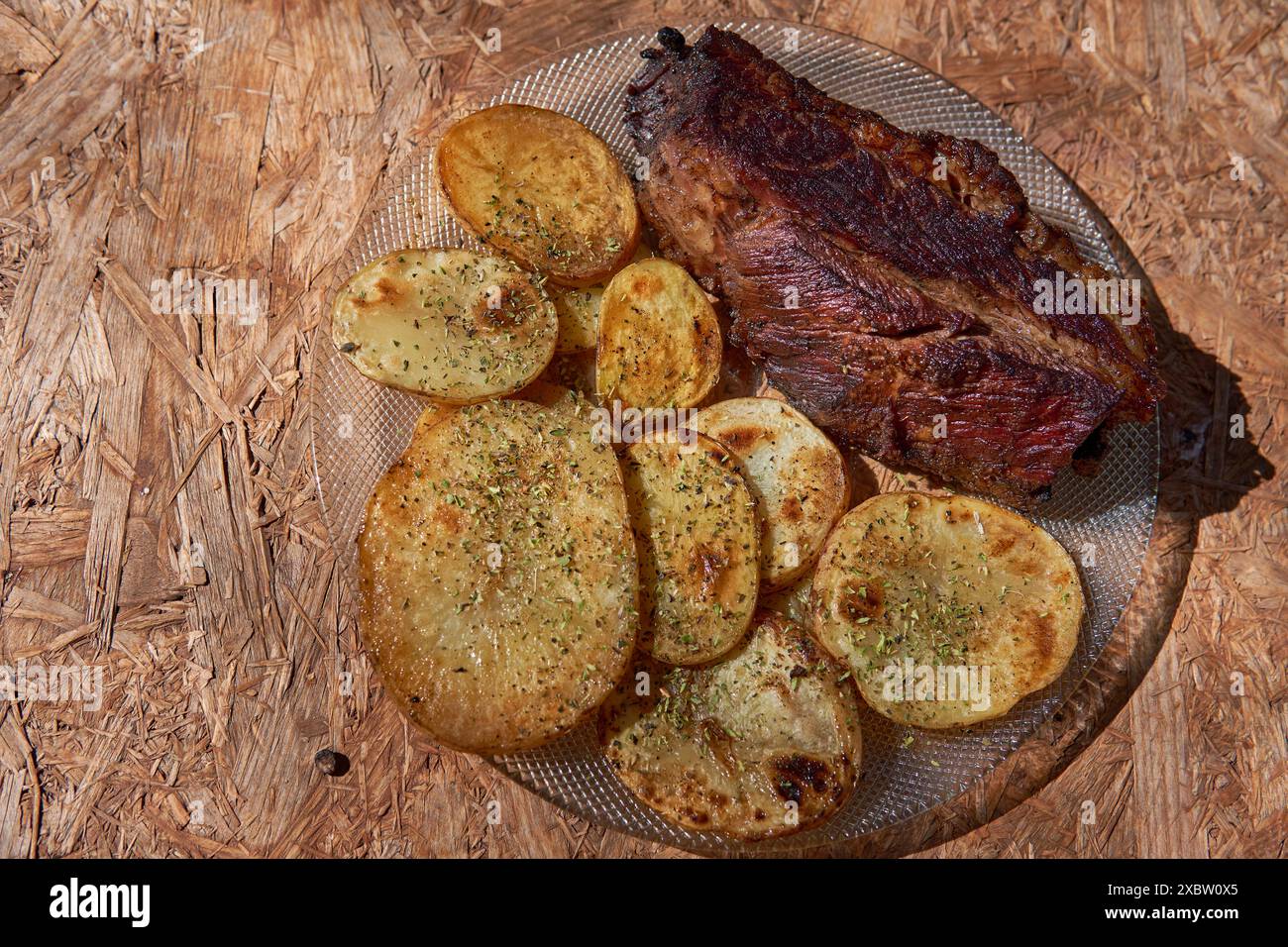 Teller Roastbeef mit rustikalen Kartoffeln mit Oregano auf rustikalem Holztisch Stockfoto