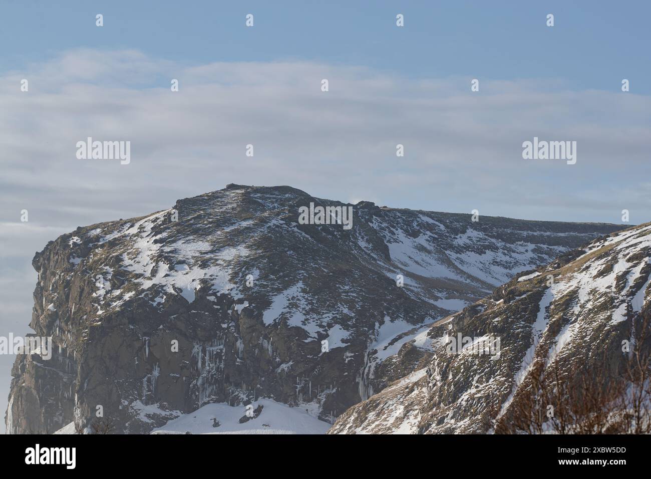 Gefrorener Wasserfall in einer schneebedeckten Berglandschaft in Island Stockfoto