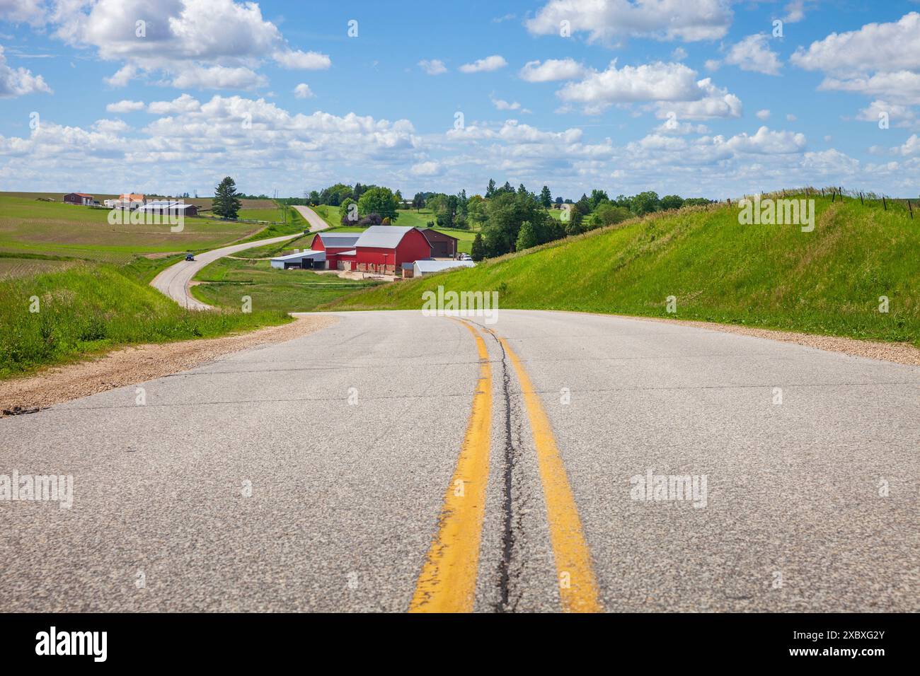 Farm mit einer roten Scheune an einer kurvenreichen Straße in der Landschaft von Iowa an einem hellen Frühlingstag Stockfoto