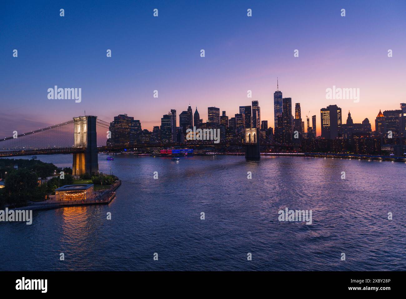 Brooklyn Bridge und New York Skyline über den East River bei intensivem Sonnenuntergang. Stockfoto