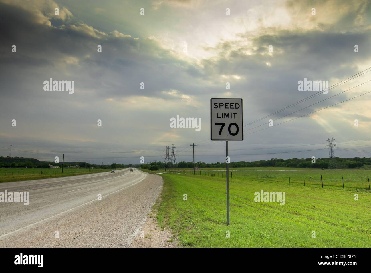 Texas Highway: Ein Schild mit einer Geschwindigkeitsbegrenzung von 70 steht vor dem Hintergrund eines dramatischen Himmels und üppigen Grüns, während die Frühlingssturmwolken dem leuchtenden Licht weichen. Stockfoto