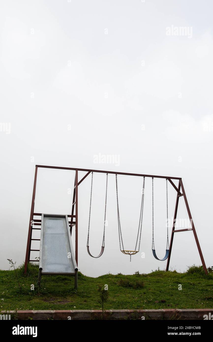 Ein Spielplatz mit Schaukeln und einer Rutsche in einem nebeligen Hintergrund, der eine gruselige, ätherische Szene schafft Stockfoto