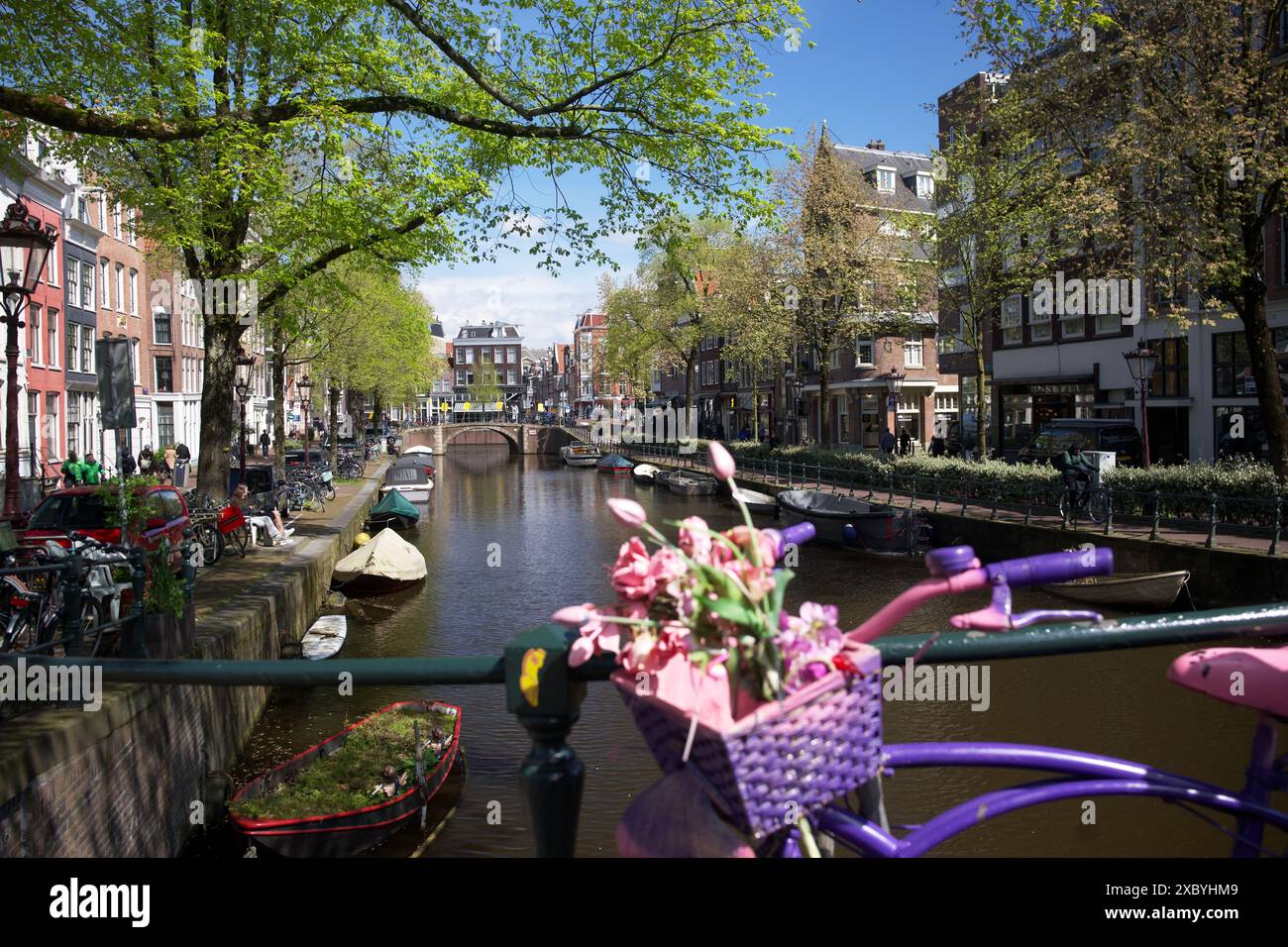 Rosafarbenes Fahrrad auf einer Brücke in Amsterdam mit Blick auf den Kanal. Frühling und sonniges Wetter in den Niederlanden Stockfoto