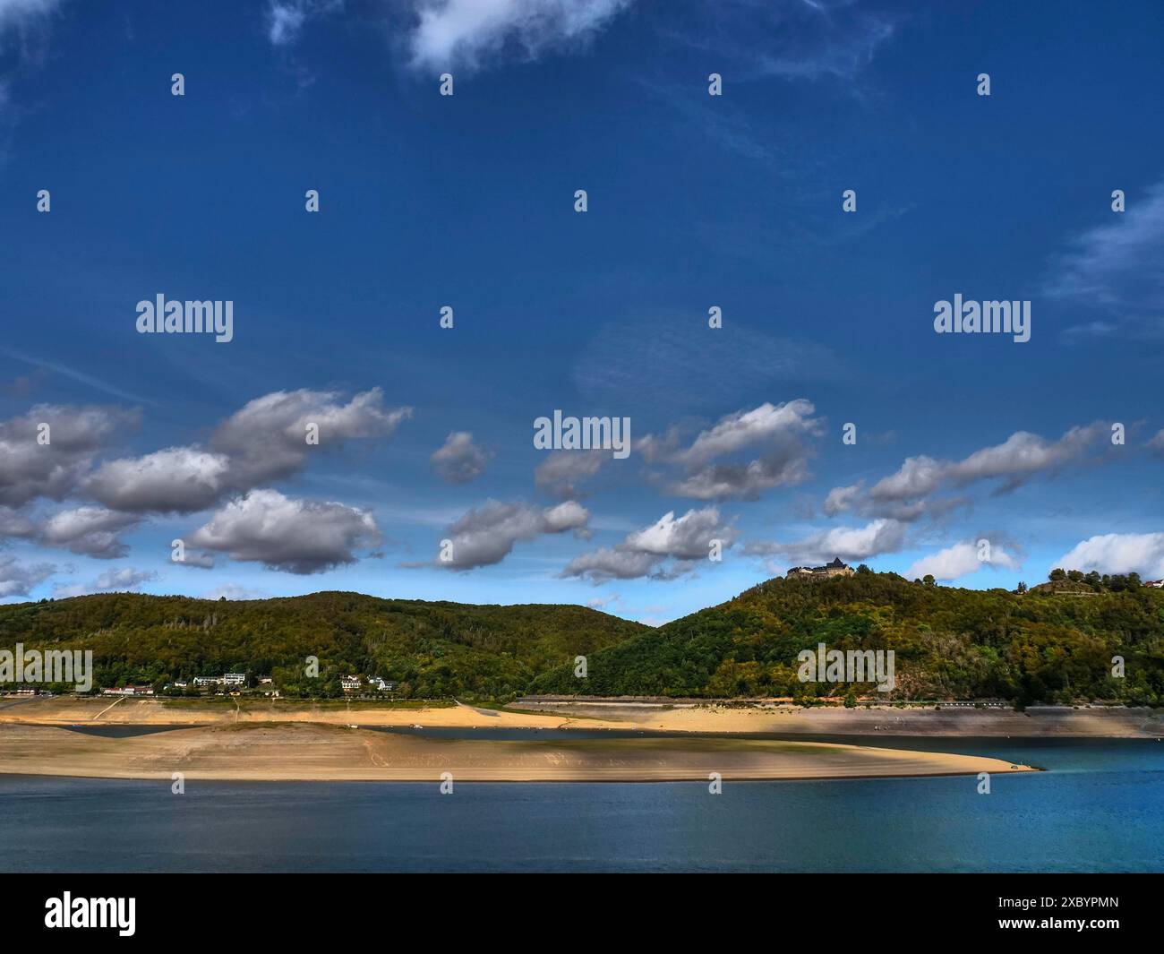 Ein ruhiger See, umgeben von bewaldeten Hügeln, umgeben von einem klaren blauen Himmel mit verstreuten weißen Wolken in einer friedlichen Landschaft, Waldeck, Hessen Stockfoto