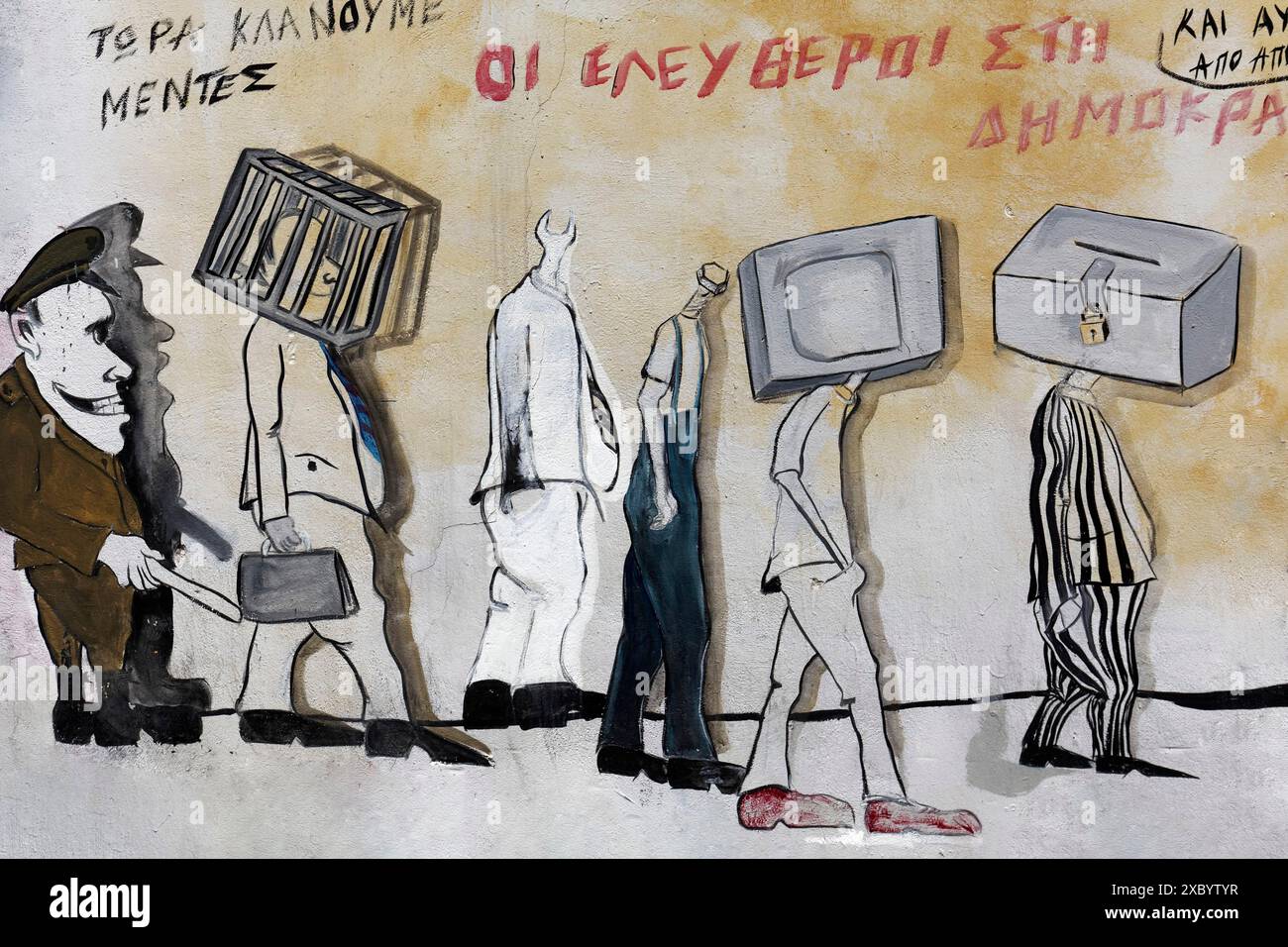 Polizist führt eine Reihe von Menschen weg, mit Kopf im Käfig, TV als Kopf, Geldbox als Kopf, ironischem Text der Freie der Demokratie, politischem Graffiti Stockfoto
