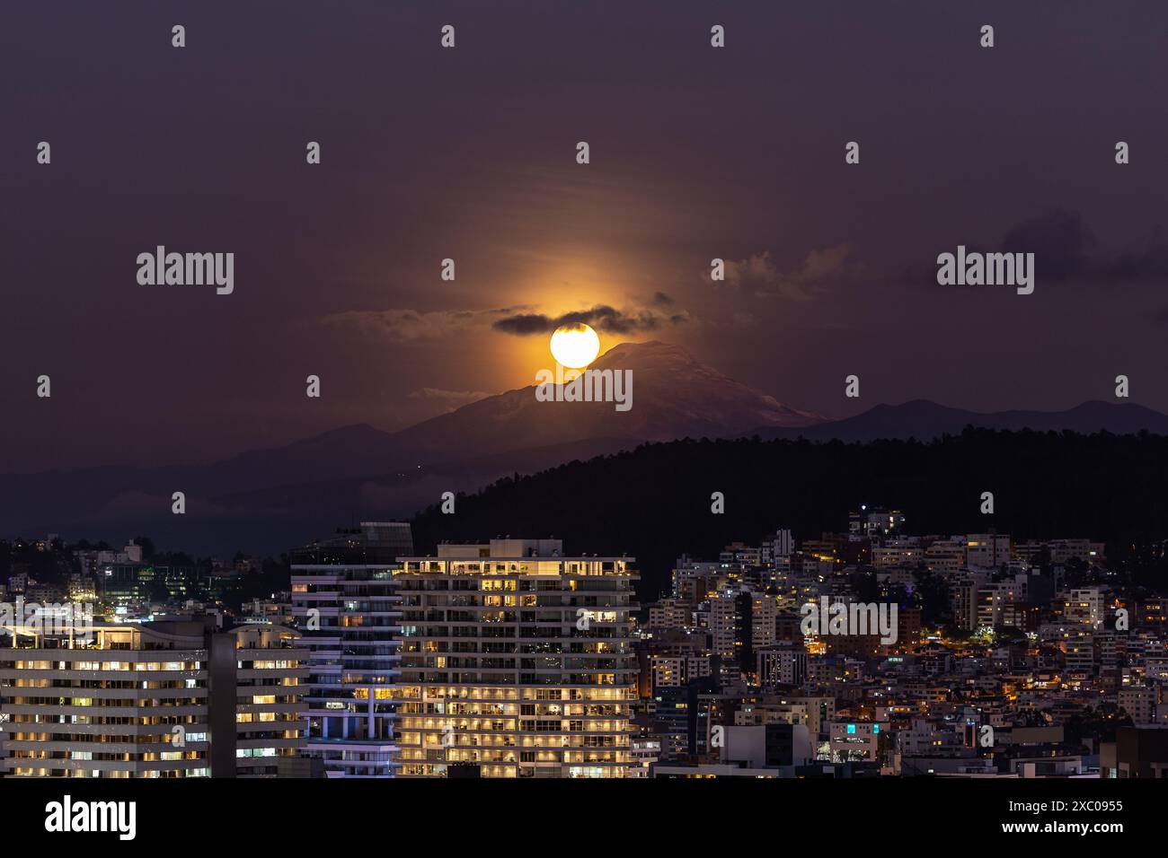 Luna llena brillante saliendo atras del volcan Cayambe en Quito Stockfoto