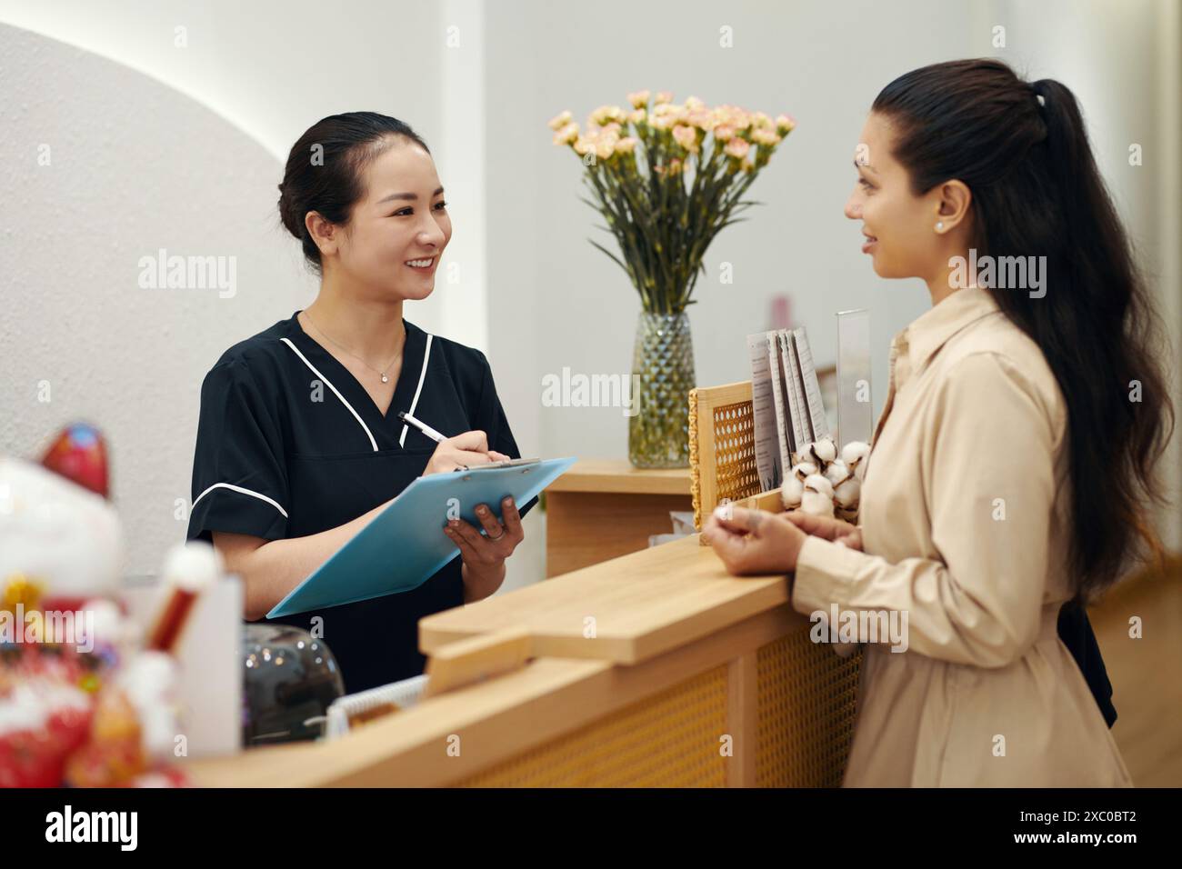Kosmetikerin im Spa-Salon spricht mit dem Kunden und füllt das Formular mit persönlichen Daten aus Stockfoto