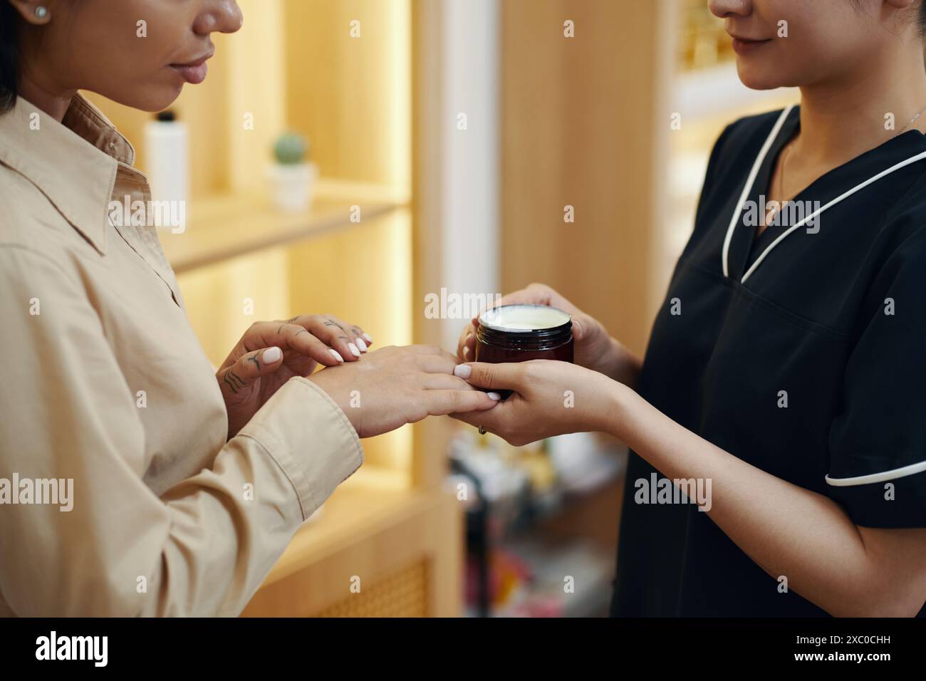Kosmetikerin, die eine feuchtigkeitsspendende, duftende Körpercreme empfiehlt Stockfoto