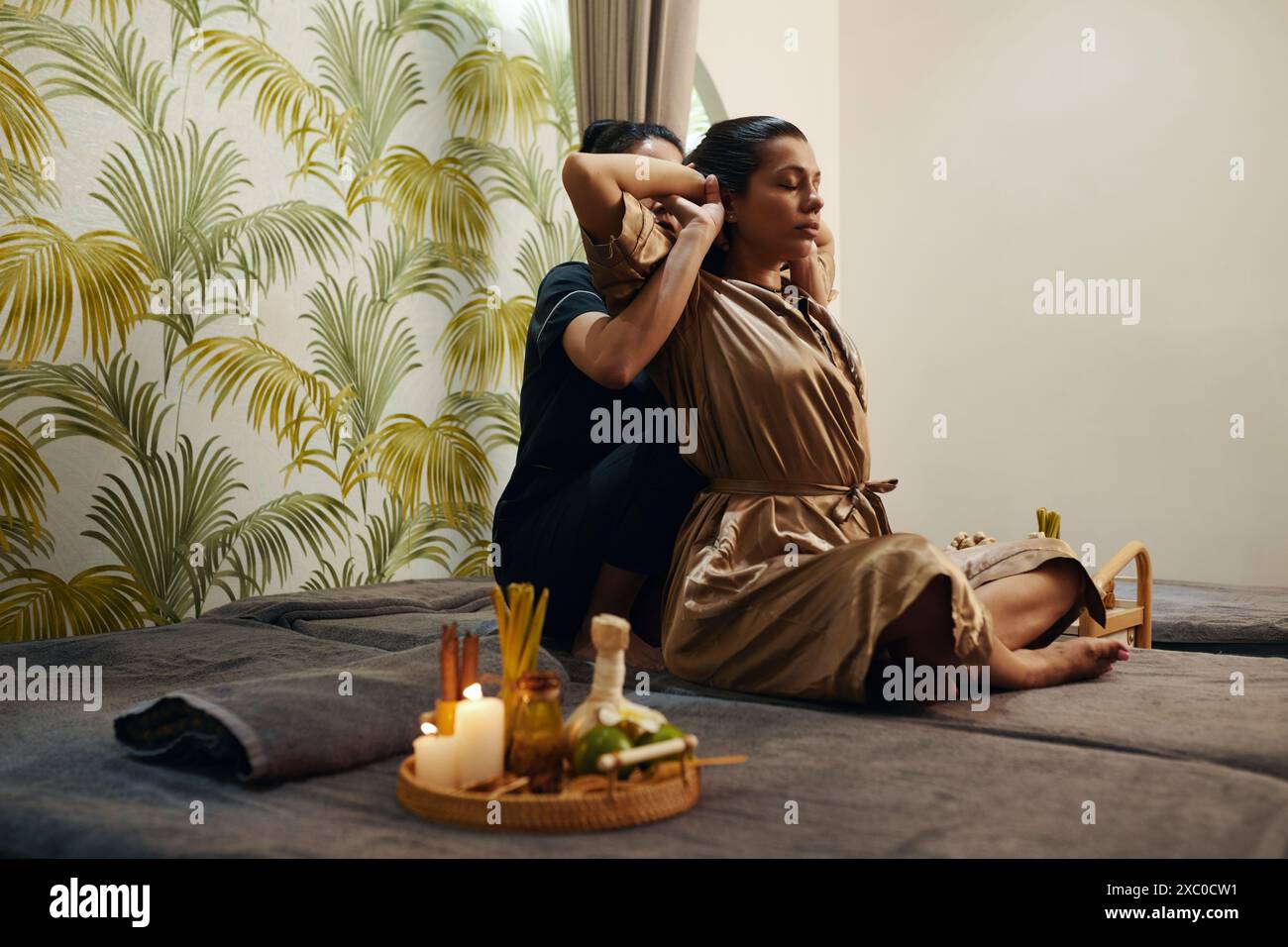 Frau im Seidenmantel genießt Rückendehnung im Spa-Salon Stockfoto