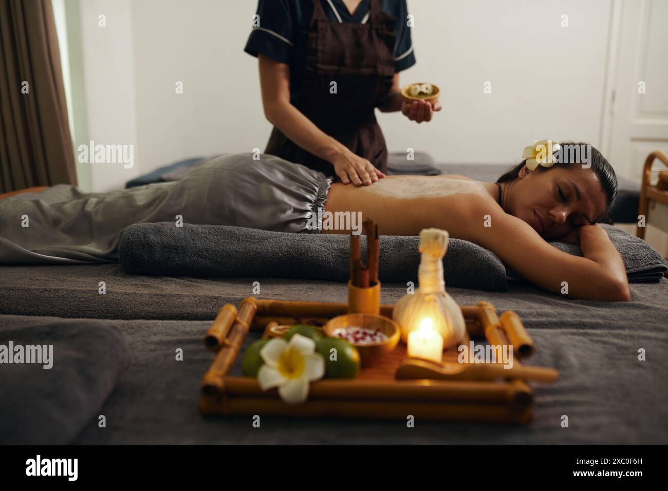 Kosmetikerin, die Salzpeeling auf den Rücken der Frau aufträgt Stockfoto