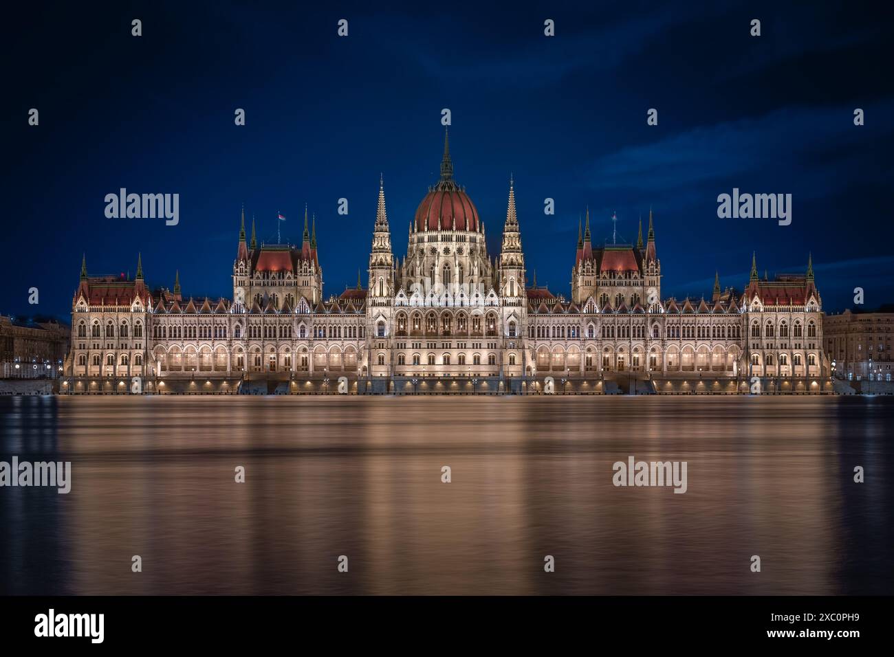 Budapest, Ungarn – beleuchtetes ungarisches Parlamentsgebäude in der Abenddämmerung. 'Orszaghaz'-Gebäude mit dunkelblauem Himmel und hohem Wasserstand wegen Überschwemmungen Stockfoto