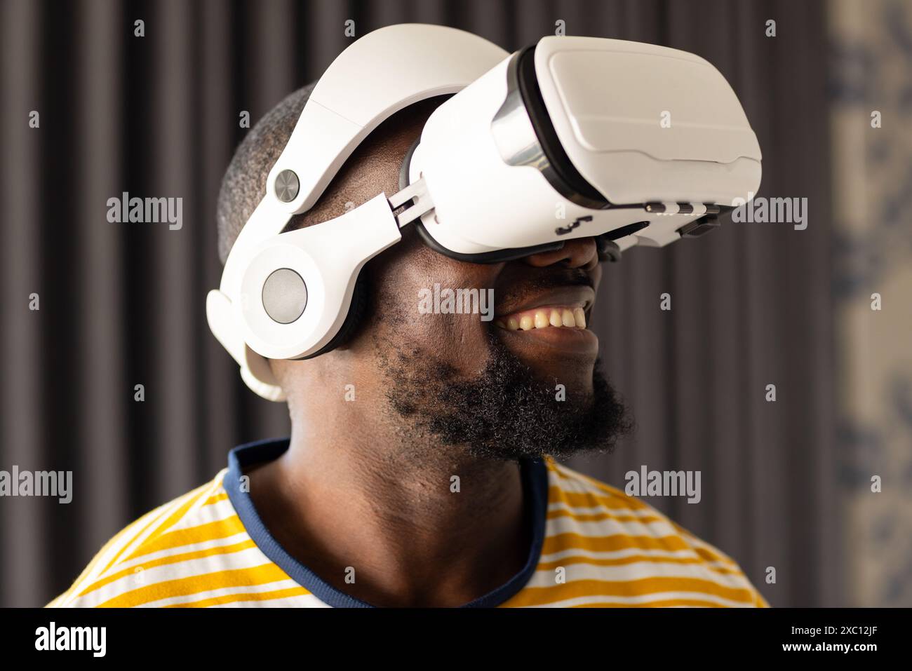 Afroamerikaner, der ein Virtual-Reality-Headset trägt, lächelnd Stockfoto