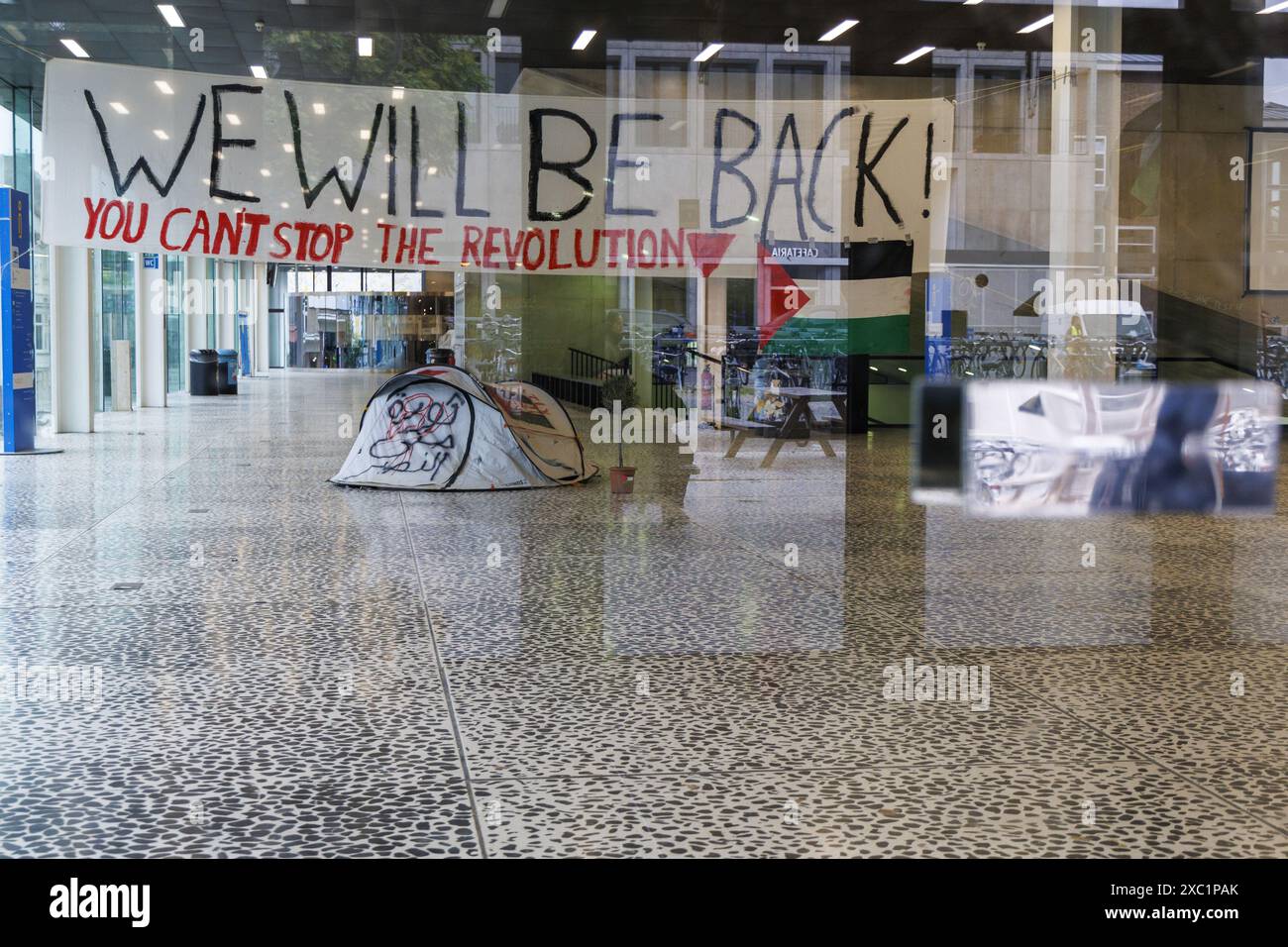 Ein einzelnes verlassenes Zelt und ein Banner mit der Aufschrift "Wir werden zurück sein" werden nach der Beendigung der Besetzung durch die Studenten zurückgelassen, um Solidarität mit dem palästinensischen Volk zu zeigen und am Freitag, den 14. Juni 2024, im Rektorat von UGent einen sofortigen Waffenstillstand im israelisch-Hamas-Konflikt in Gent zu fordern. Gestern hat das Berufungsgericht Gent den Antrag auf Räumung pro-palästinensischer Dämonen aus dem UFO-Gebäude in UGent für gerechtfertigt erklärt und den Besatzern 12 Stunden nach Verkündung des Urteils gegeben, die Räumlichkeiten der Universität Gent zu verlassen. BELGA FOTO NICOLAS MAETERLINCK Stockfoto