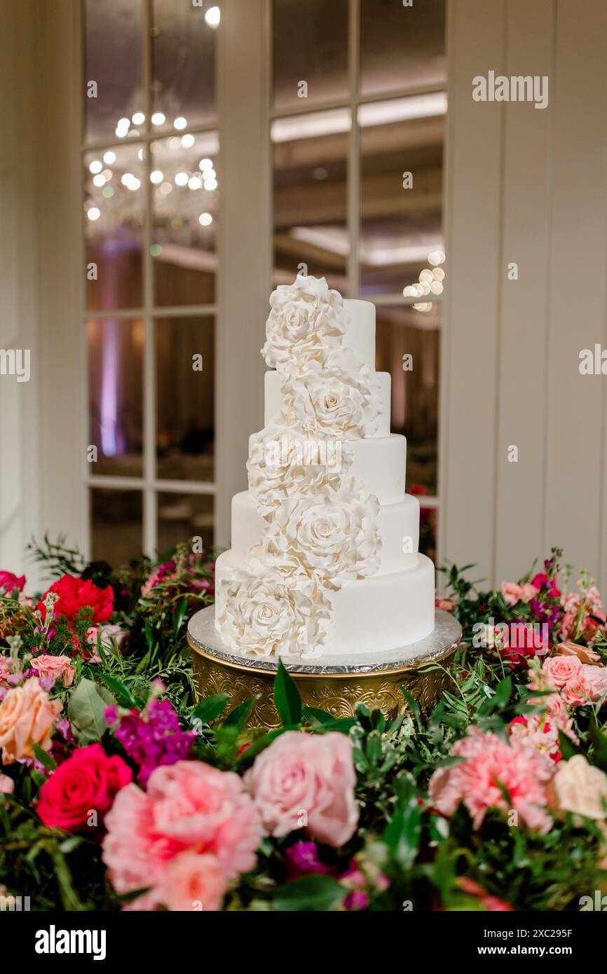 Weiße Hochzeitstorte mit Blumen aus Glasur und bunten Blumenstrauß Stockfoto