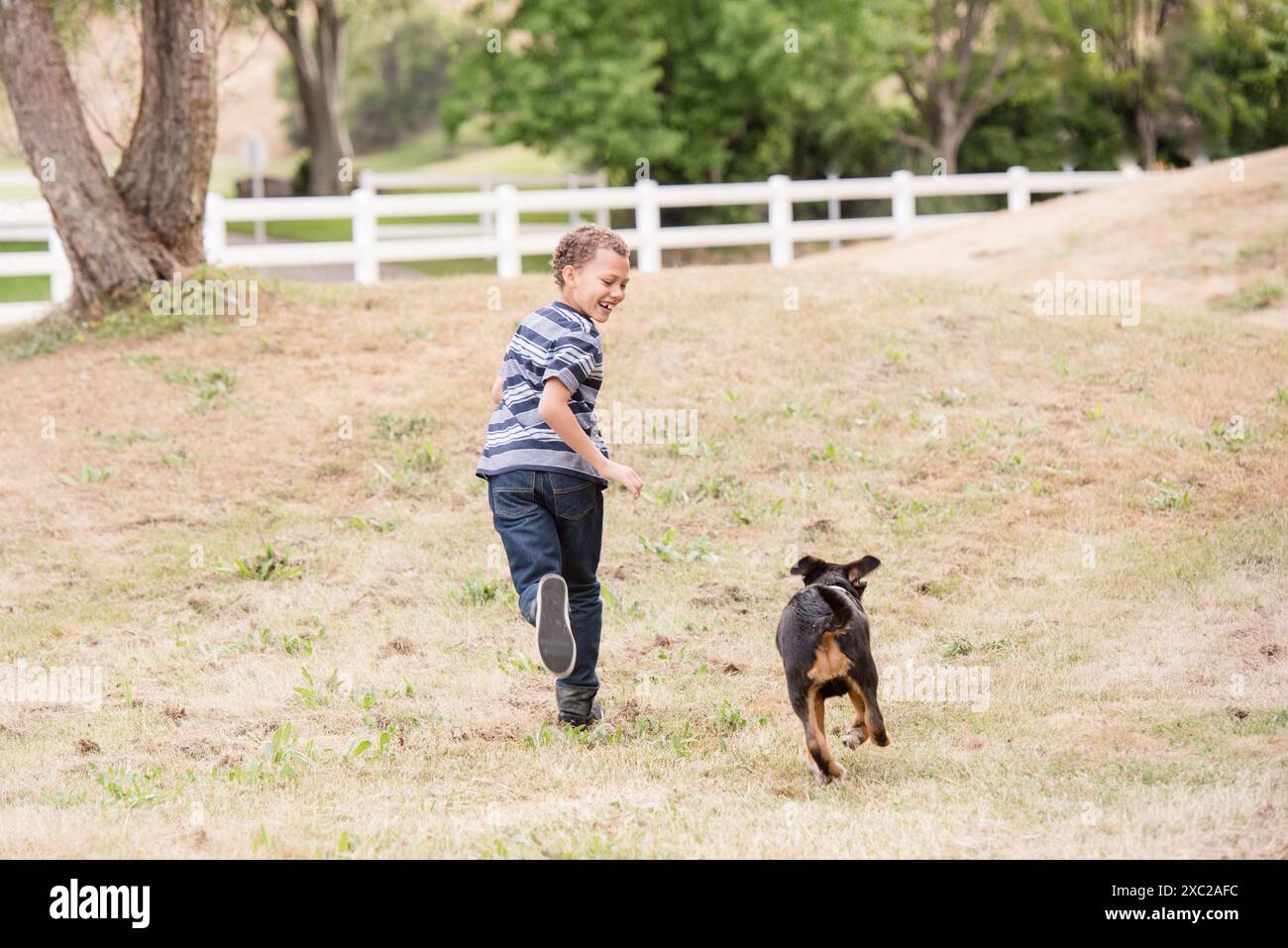 Junge und Hund laufen zusammen lachend Stockfoto