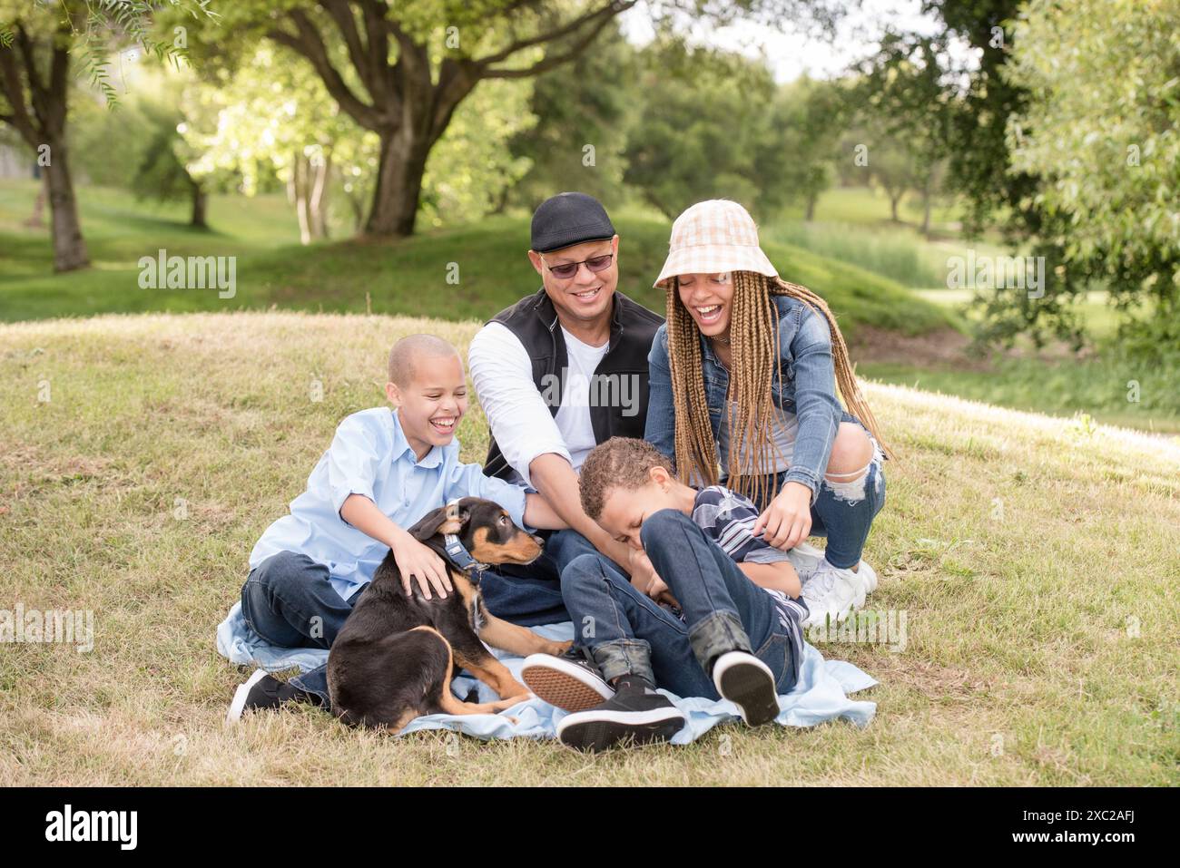Vierköpfige Familie mit lachendem und kitzelndem Jungen und Hund Stockfoto