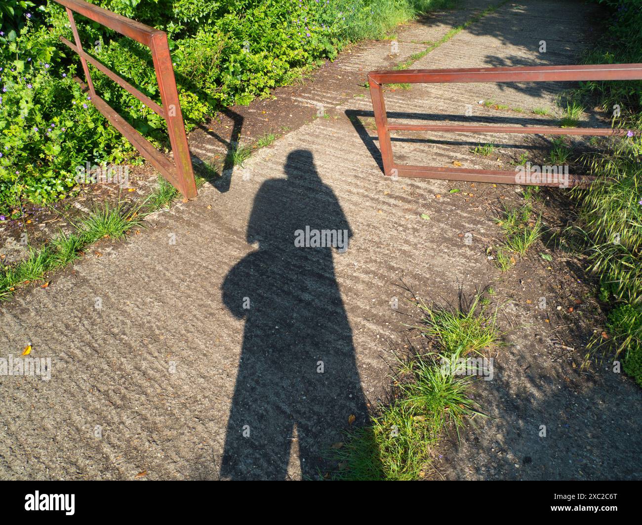 Mein Schatten und ein offenes Fußwegentor begrüßen mich auf einem meiner Lieblingswanderungen von meinem Heimatdorf Radley in Oxfordshire hinunter zur Themse. Stockfoto
