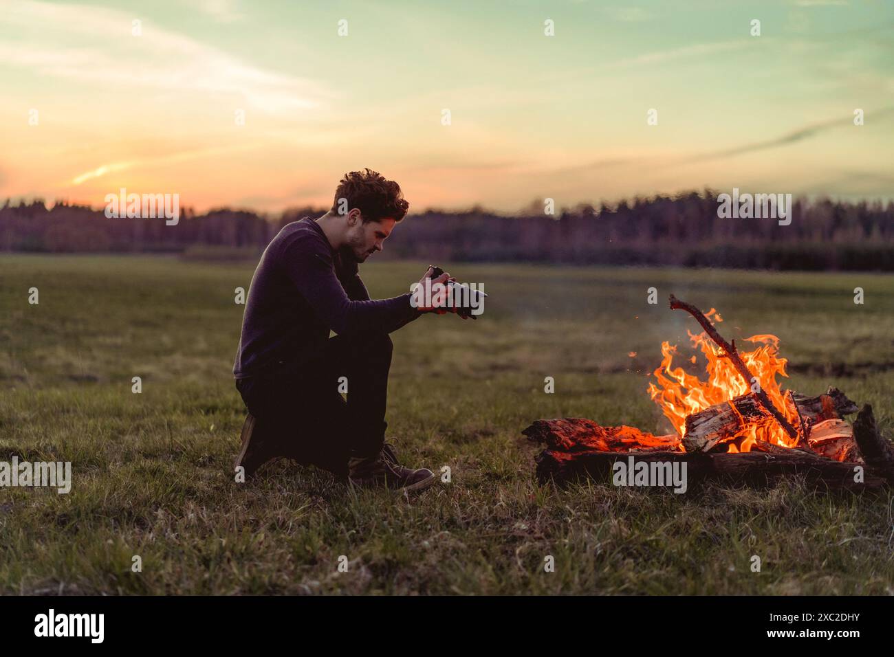 Der Mann fotografiert ein Lagerfeuer, einen Campingausflug. Stockfoto