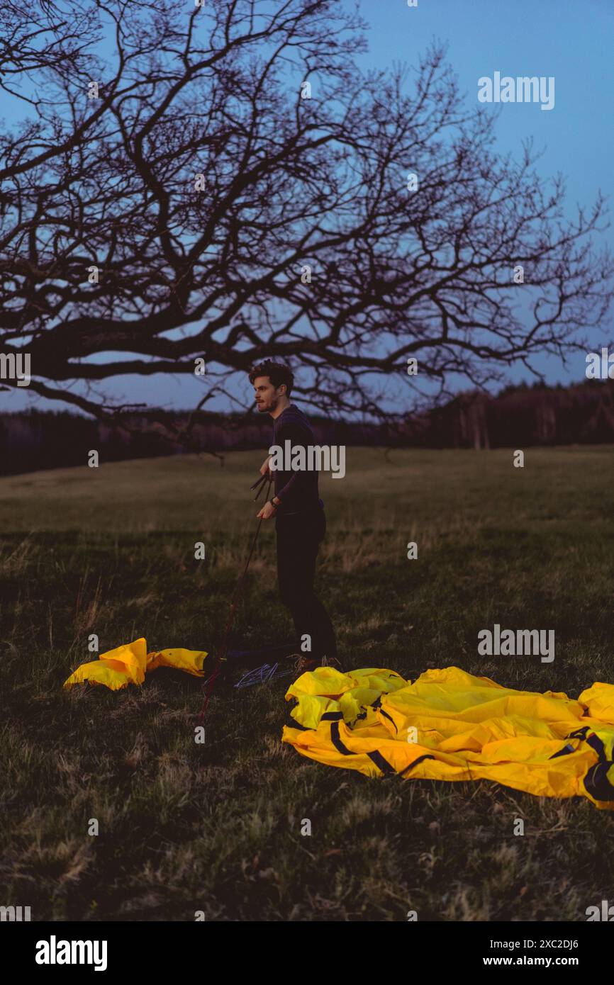 Ein Mann baut ein Zelt auf einem Campingausflug im Wald. Stockfoto