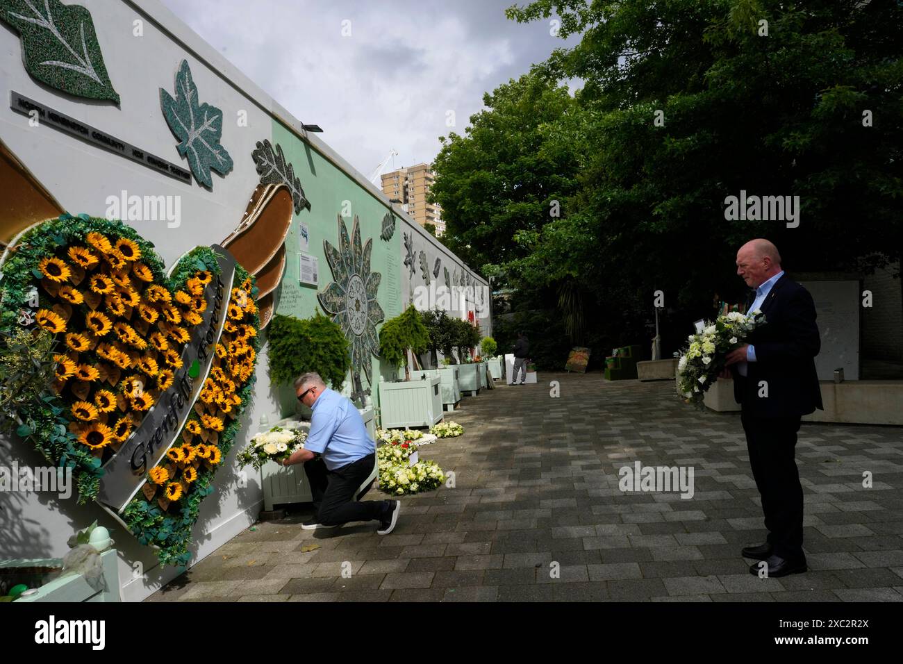 Matt Wrack, General Secretary of the Fire Brigades Union, right, and Gareth Beeton London Regional Chair of the Fire Brigades Union, left, lay wreaths at the Grenfell Tower memorial wall on the seventh anniversary of the fire, in North Kensington, London, Friday, June 14, 2024. On June 14, 2017, fire ripped through the 24-story Grenfell Tower in West London, killing at least 72 people. (AP Photo/Kirsty Wigglesworth) Stockfoto