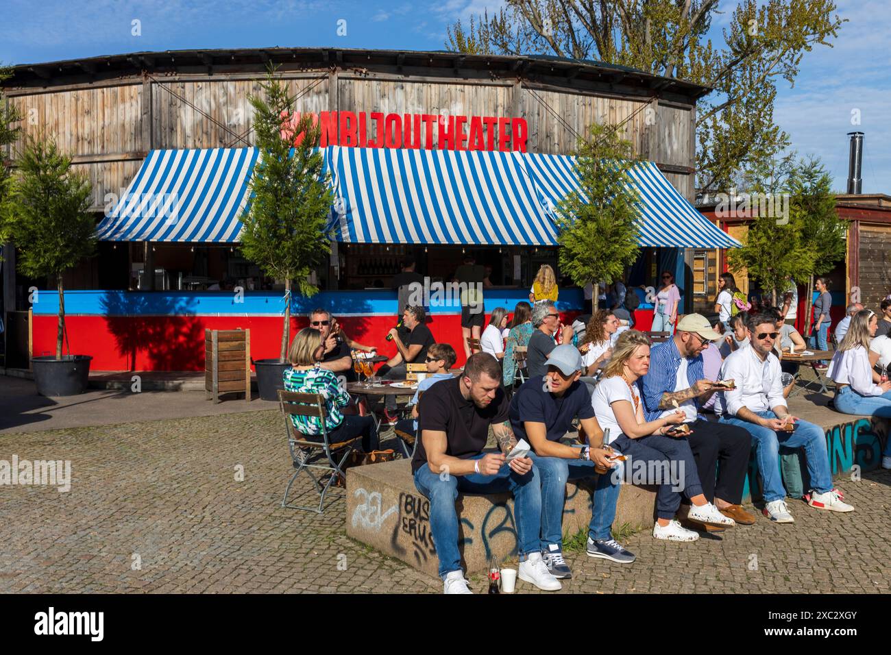 Berlin, Deutschland - 2. April 2024, Café in der Nähe des Monbijou-Theaters. Die Leute sitzen auf Bänken, schauen auf den Fluss, trinken Bier. Stockfoto