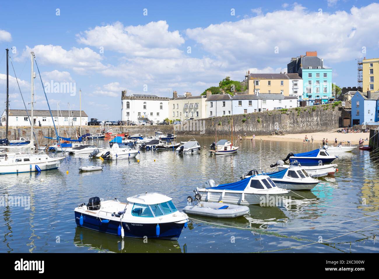 Kleine Boote in Tenby Harbour und Tenby Harbour Beach bei Flut mit Tenby farbenfrohen Häusern Tenby Carmarthan Bay Pembrokeshire West Wales UK GB Stockfoto