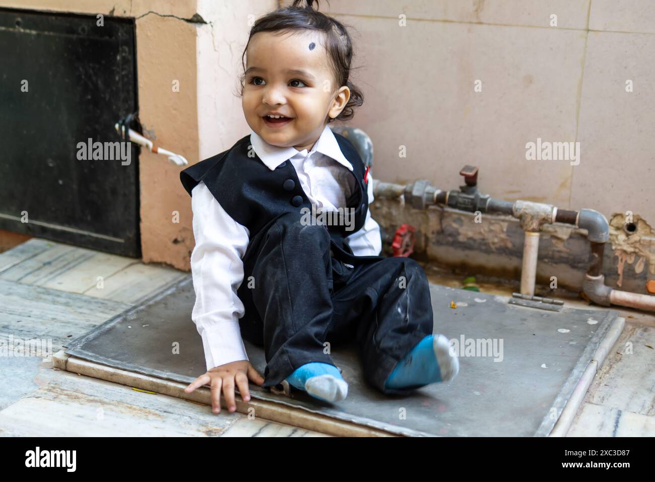 Niedliches indisches Kleinkind Baby Junge in schwarzem Anzug im Freien aus verschiedenen Blickwinkeln Stockfoto