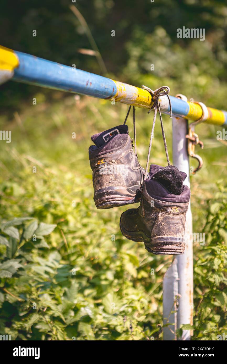 Ein Paar Wanderschuhe hängen an den Schnürsenkeln an einem Boom-Tor Stockfoto