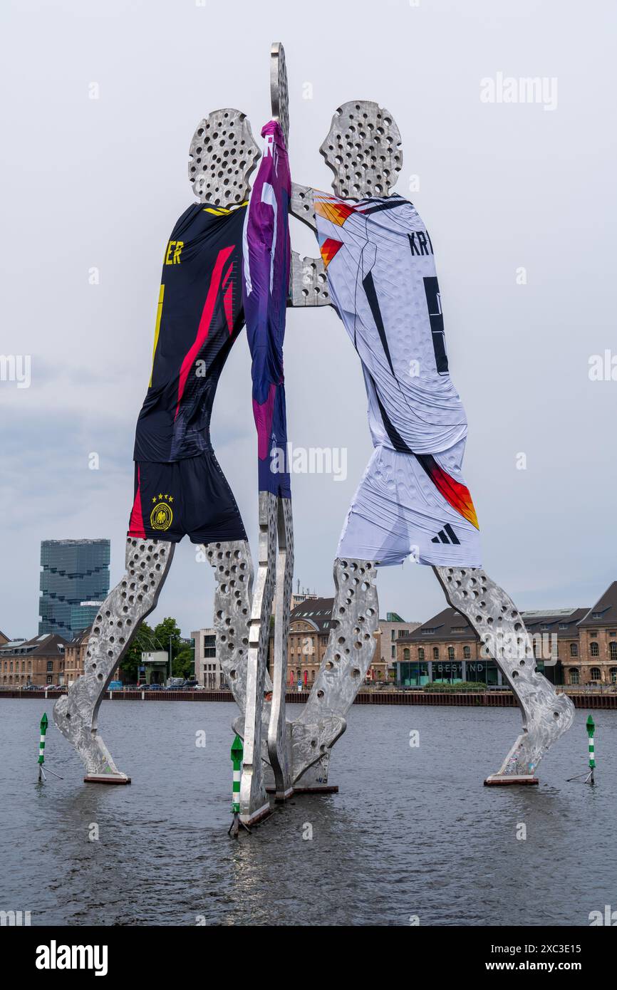 Anlässlich der Fußball-Europameisterschaft 2024 wurde die Skulptur „Moleculeman“ an der Spree mit Trikots der deutschen Nationalmannschaft verziert. Stockfoto