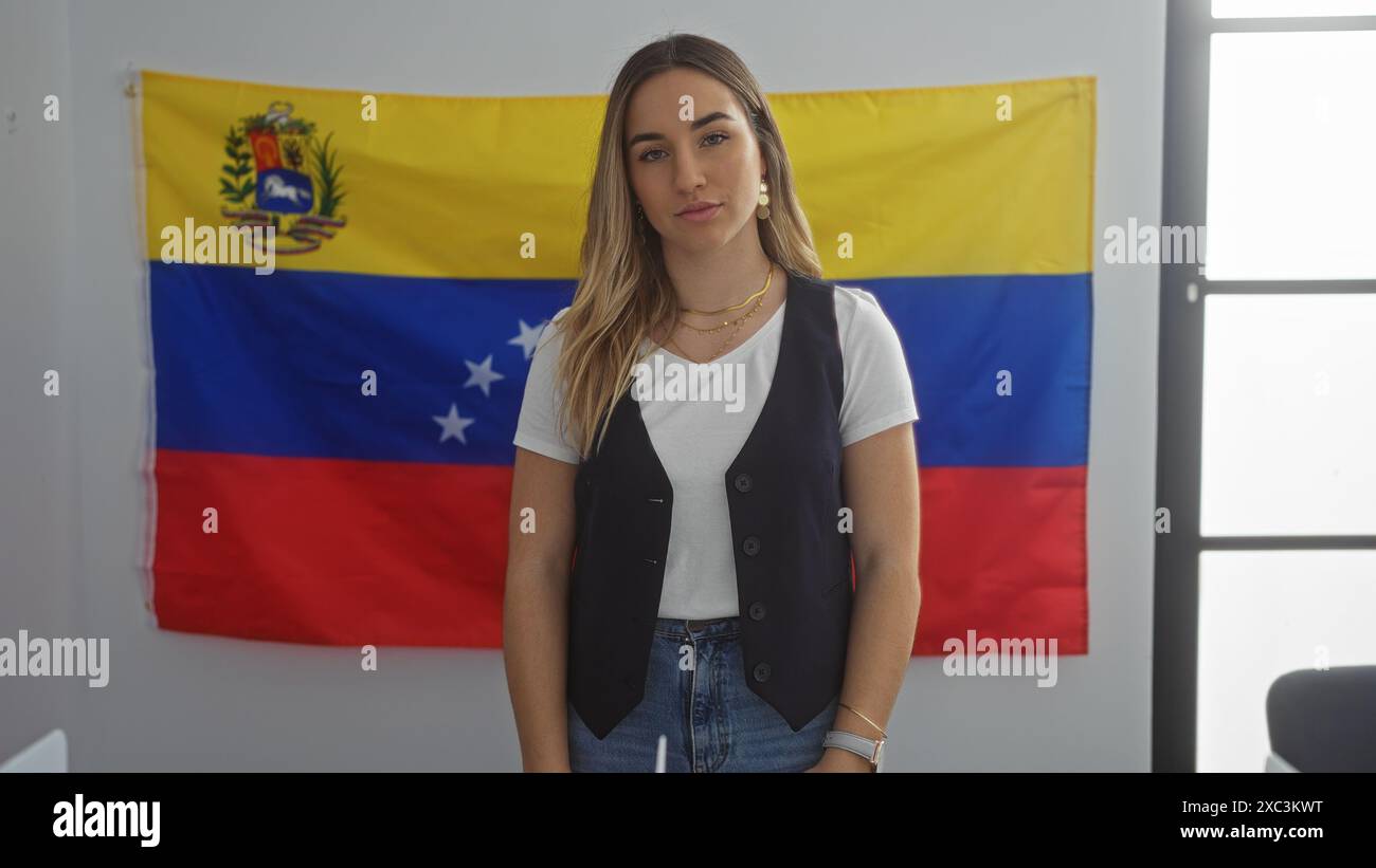 Attraktive junge Frau, die in einem Wahlhaus steht, mit einer venezolanischen Flagge im Hintergrund, die eine schöne und selbstbewusste Erwachsene Frau verkörpert Stockfoto