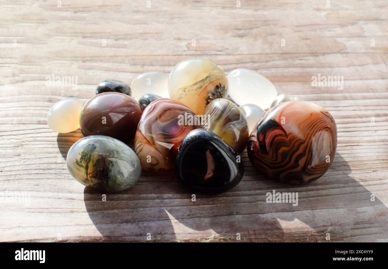 Heilkristalle auf einem alten hölzernen Hintergrund. Botswana-Achat. Mehrfarbige Edelsteine, Mineralien. Achate unterschiedlicher Größe. Stockfoto