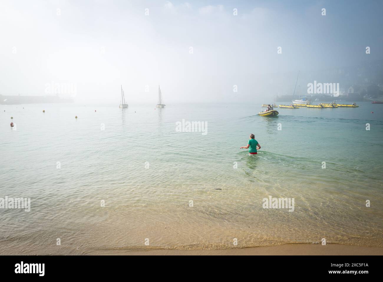 St Ives, Cornwall, Großbritannien. Blick auf den Hafen mit frühmorgendlichem Schwimmer und Meeresnebel, der hereinbricht. Stockfoto