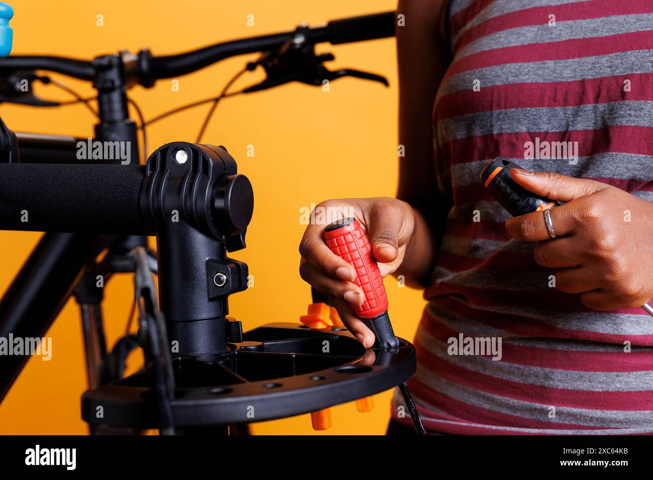 Aus nächster Nähe: afroamerikanische weibliche Hand, die wichtige Ausrüstung für die Fahrradwartung organisiert. Sportbegeisterte, kompetente Einzelprüfung und Anfertigung spezieller Werkzeuge. Stockfoto