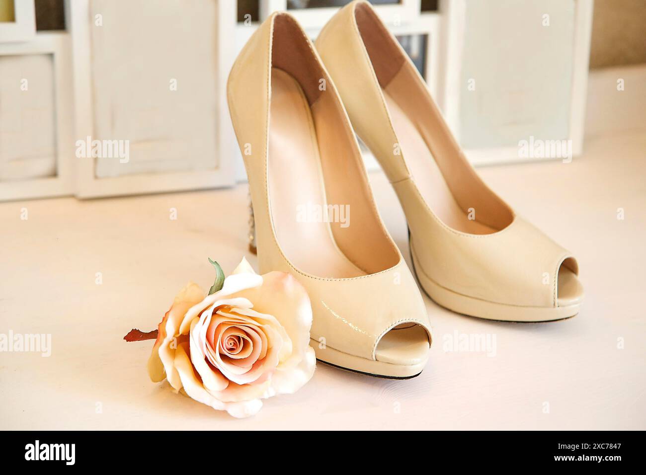 Elegante beige High Heels kombiniert mit zarter Rose in einem weichen, femininen Ambiente Stockfoto