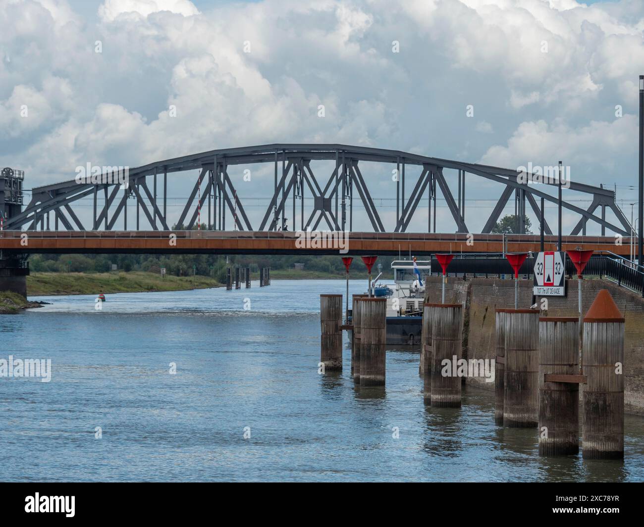 Eine Metallbrücke über einen Fluss mit industrieller Umgebung und Wolken am Himmel, zutphen, gelderland, niederlande Stockfoto