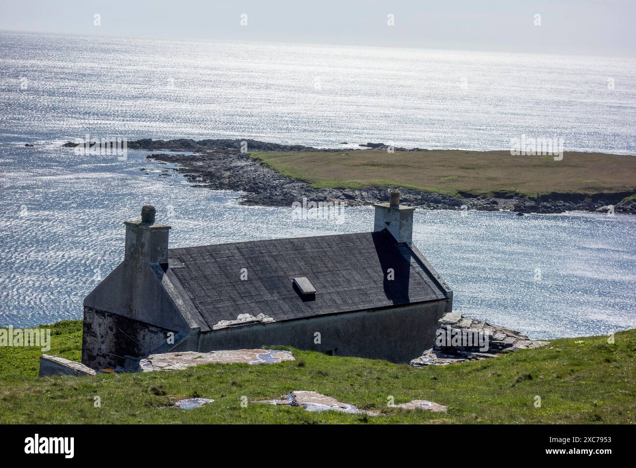 Ein Haus an einer ruhigen Küste mit Blick auf das breite blaue Meer, lerwick, shetlands, Schottland, Großbritannien Stockfoto