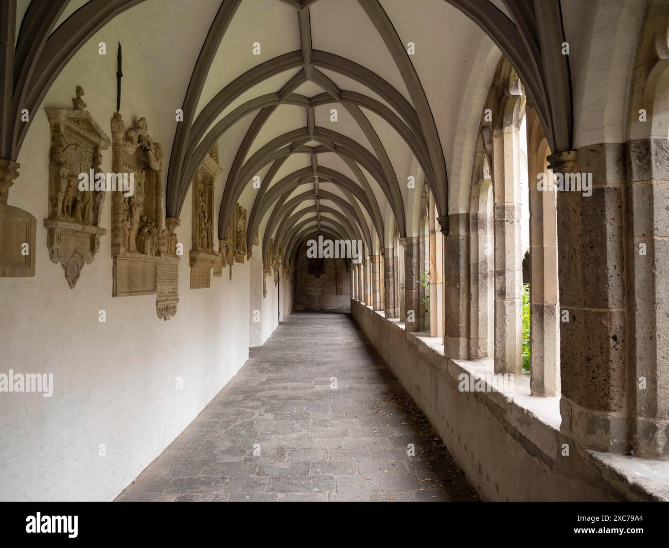 Ein ruhiger Korridor mit gotischen Bögen und Reliefs an den Steinmauern eines historischen Klosters, Xanten, Nordrhein-Westfalen, Deutschland Stockfoto