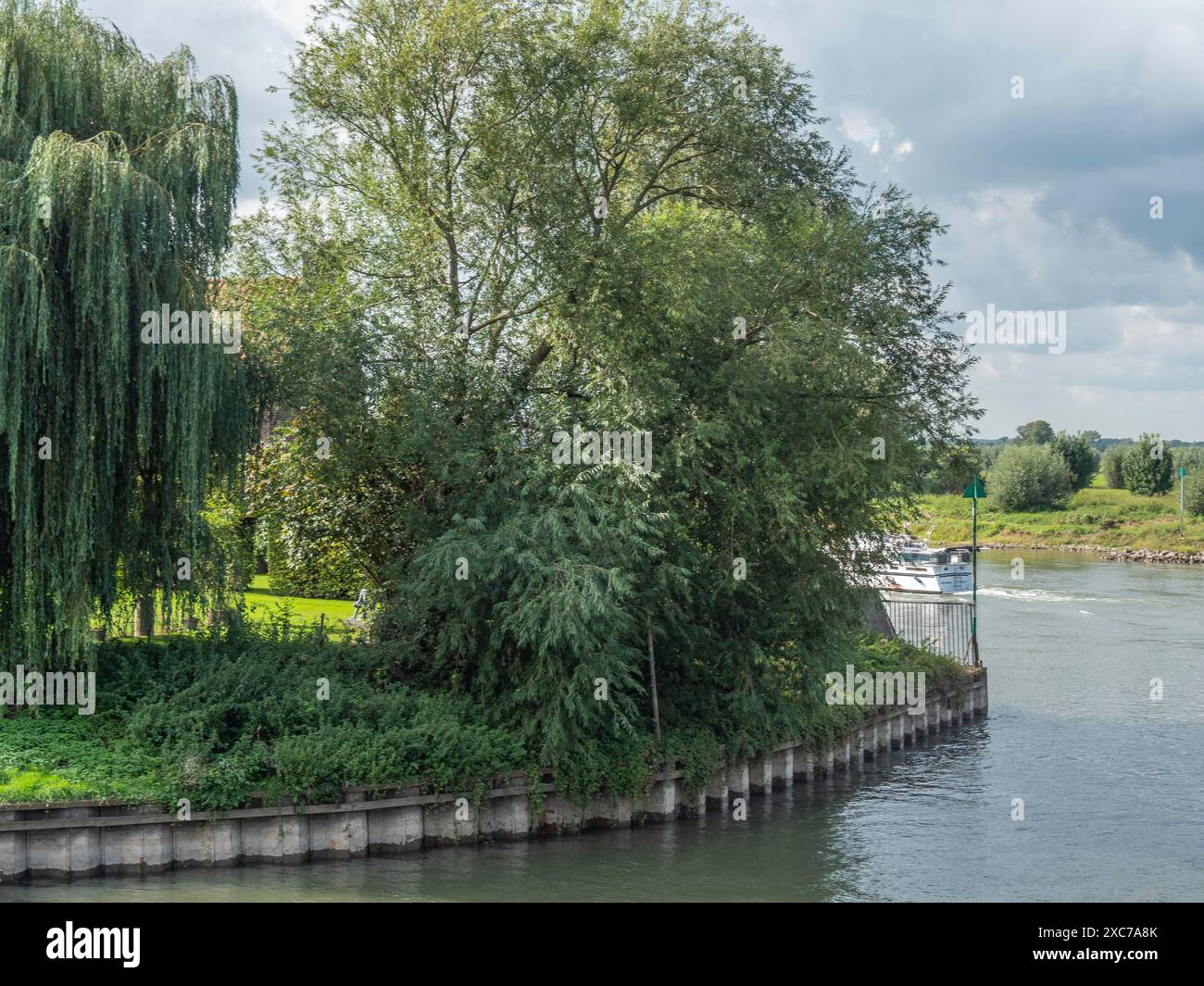 Ein Fluss fließt leise um eine bewachsene Kurve im Ufer, umgeben von üppig grünen Bäumen, zutphen, gelderland, niederlande Stockfoto