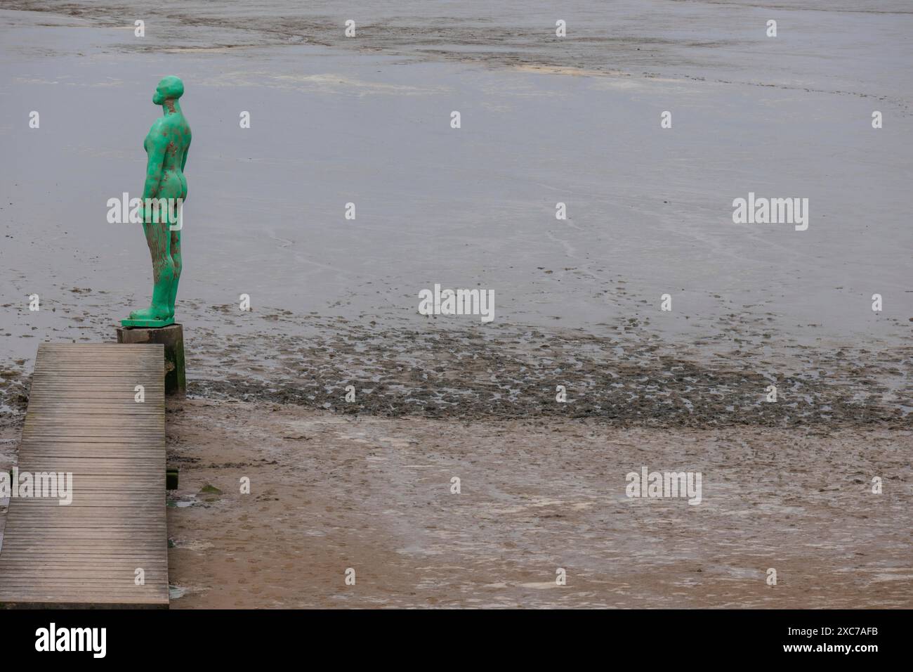 Eine grüne Statue auf einem Holzsteg mit Blick auf das ruhige Meer und den Strand, Dangast, varel, deutschland Stockfoto