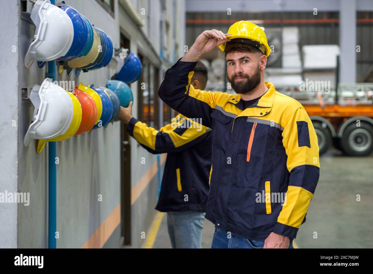 Zwei Leute arbeiten in einer Fabrik. Aus Sicherheitsgründen tragen sie einen Schutzhelm auf dem Kopf. Konzept der Arbeitssicherheit. Bauindustrie. Stockfoto