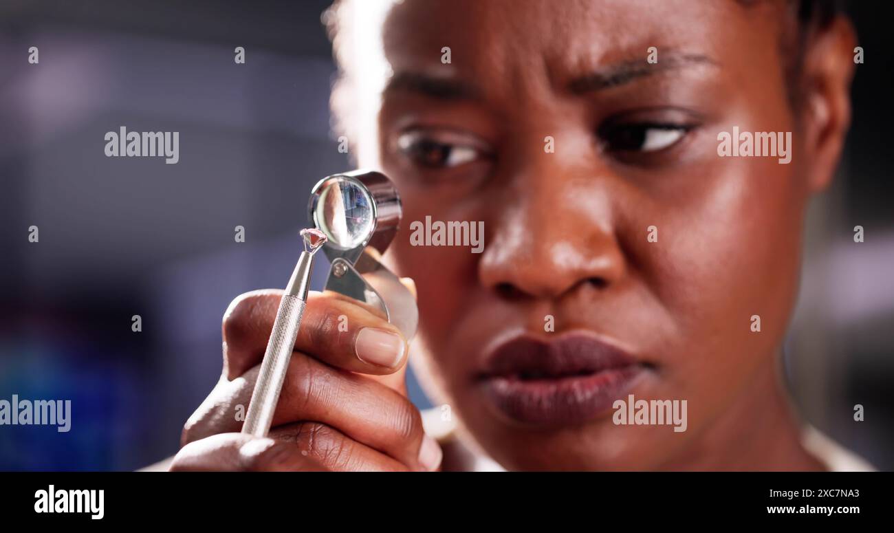 Diamantinspektor untersucht Qualität durch Lupen in afroamerikanischer Juwelierwerkstatt. Frau, Die Den Wert Von Edelsteinen Mit Präzisionswerkzeugen Bewertet. Stockfoto