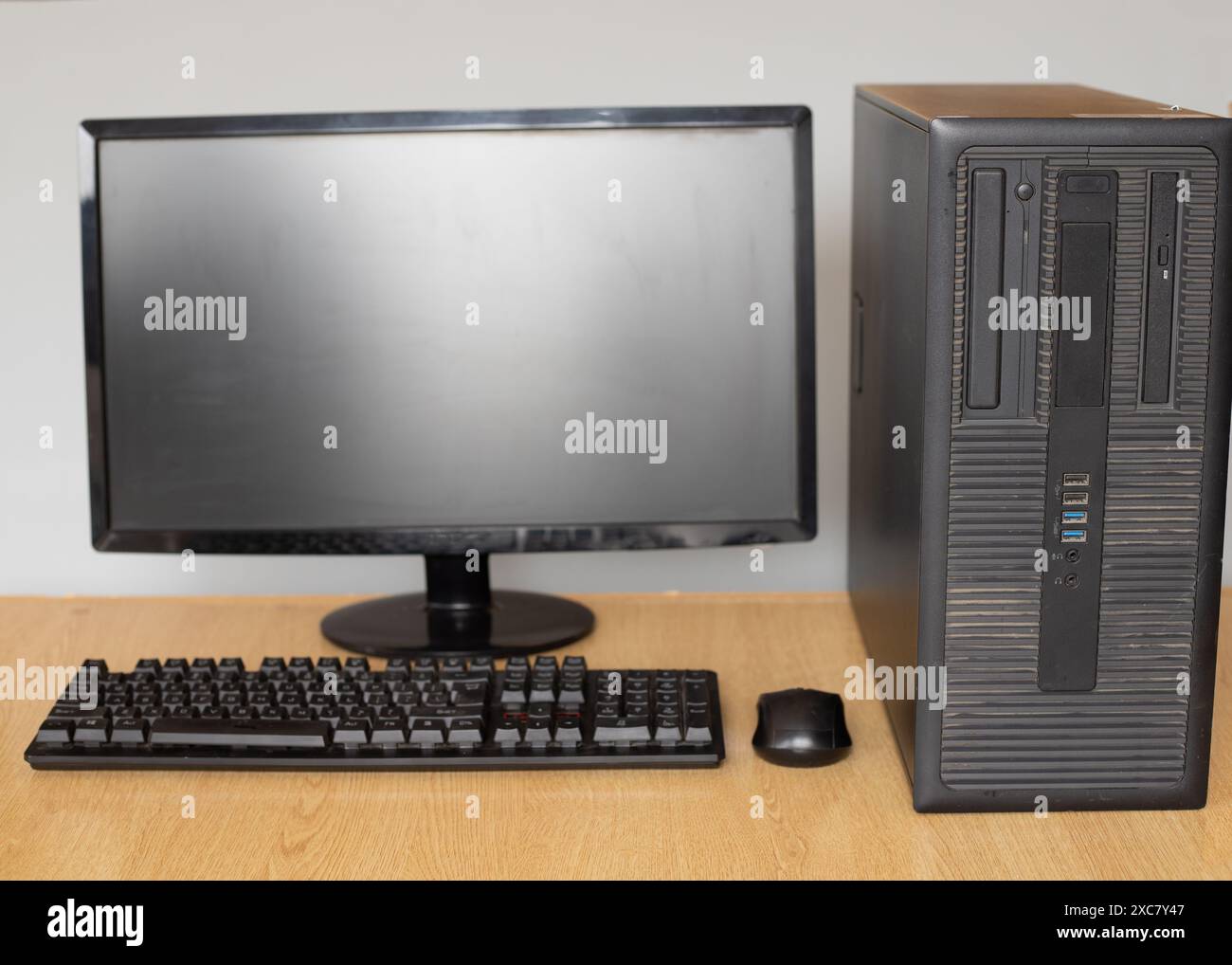 Computermonitor, mit Tastatur und Maus auf einem Holztisch. Stockfoto