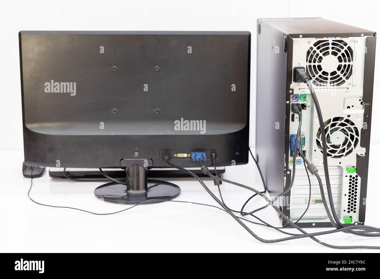 Rückansicht eines Desktop-Computers und Monitors mit angeschlossenen Kabeln. Rückansicht mit angeschlossenen Kabeln. Stockfoto