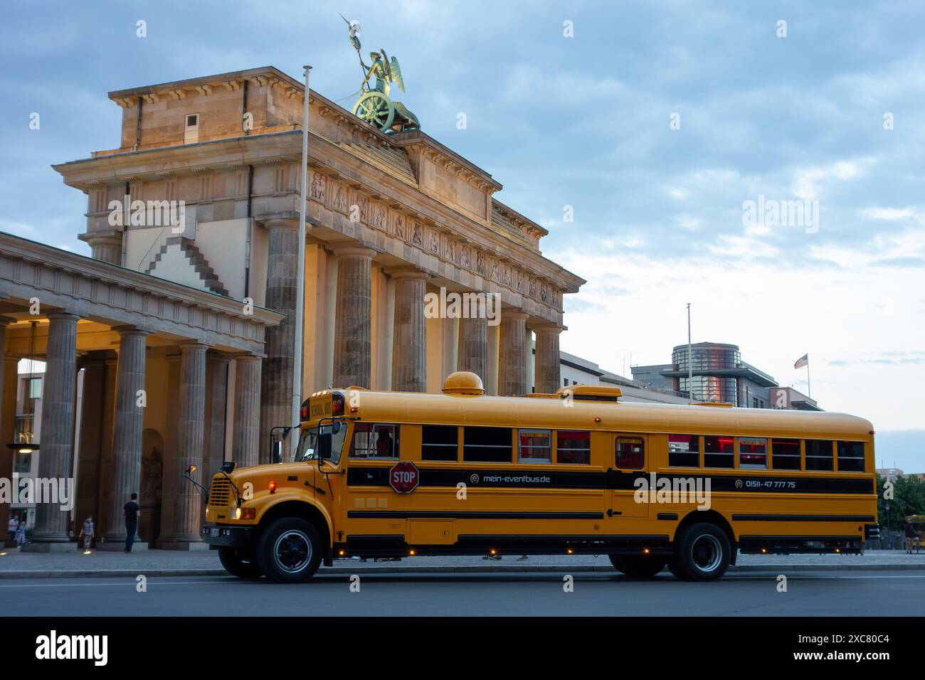 BERLIN, DEUTSCHLAND - 6. AUGUST 2016: Amerikanischer gelber Schulbus International 3800 von Mein-Eventbus.de Unternehmen vor dem Brandenburger Tor in der Abenddämmerung Stockfoto