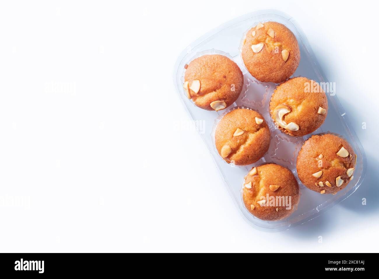 Frisch gebackene Mandelmuffins in einer transparenten Kunststoffschale auf weißem Hintergrund. Draufsicht Stockfoto
