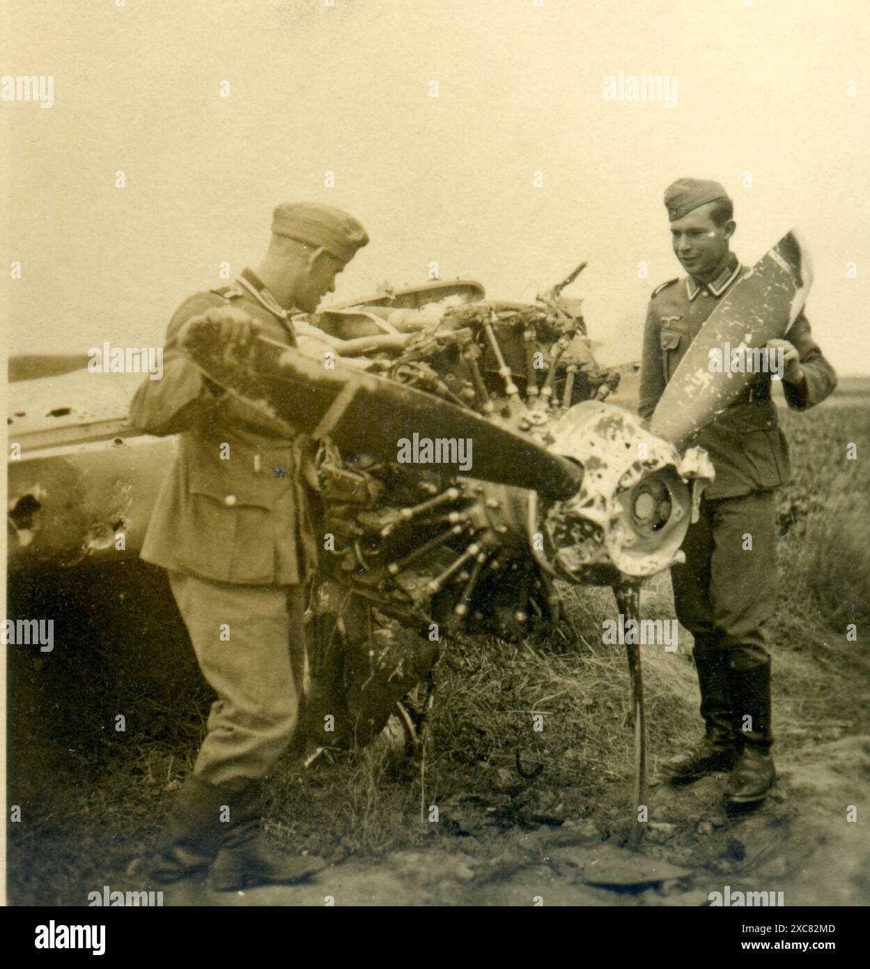 Zwei deutsche Soldaten untersuchen ein zerstörtes Flugzeug, IIWW Stockfoto