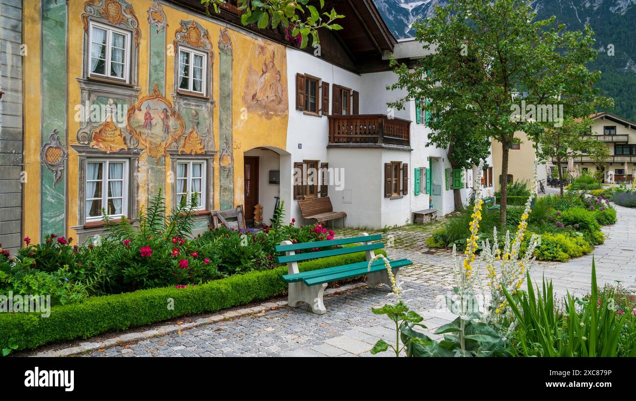 Die Marktgemeinde Mittenwald mit historischen Gebäuden Mittenwald liegt im Landkreis Garmisch-Partenkirchen, ist Deutschlands höchstgelegener Luftkurort und berühmt wegen der traditionellen Kunst des Geigenbaus. In der historischen Altstadt sind viele Häuser auf der Fassade mit kunstvoller Lüftlmalerei geschmückt. Direkt neben der historischen Altstadt liegt der Ortsteil Gries mit seinen historischen Gebäuden und den mit Blumen- und Pflanzenschmuck aufwendig gestaltete Freiflächen. Mittenwald Bayern Deutschland *** die Marktstadt Mittenwald mit historischen Gebäuden Mittenwald befindet sich in Stockfoto