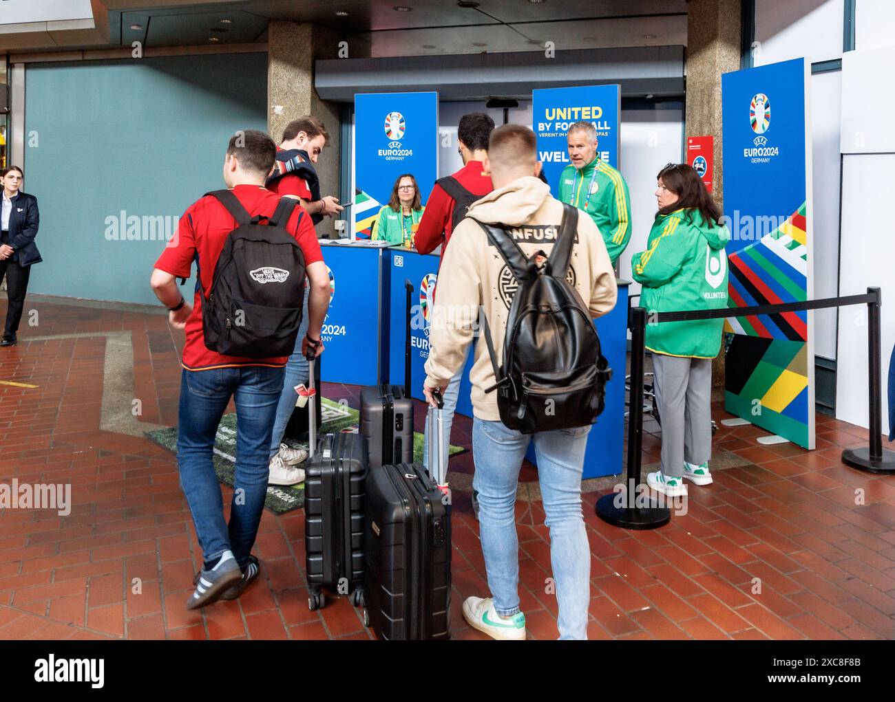 Hamburg, Deutschland. Juni 2024. Spanische Fußballfans kommen an den „Welcome Desks“ der Deutschen Bahn am Hauptbahnhof an. Einen Tag vor dem ersten Spiel der Fußball-Europameisterschaft in Hamburg hat die Deutsche Bahn am Hauptbahnhof einen Unterstützungsservice für Fans gestartet. Hier beraten DB-Mitarbeiter internationale Fans bei ihrer Ankunft und bei allen Themen rund um die Europameisterschaft 2024. Quelle: Markus Scholz/dpa/Alamy Live News Stockfoto